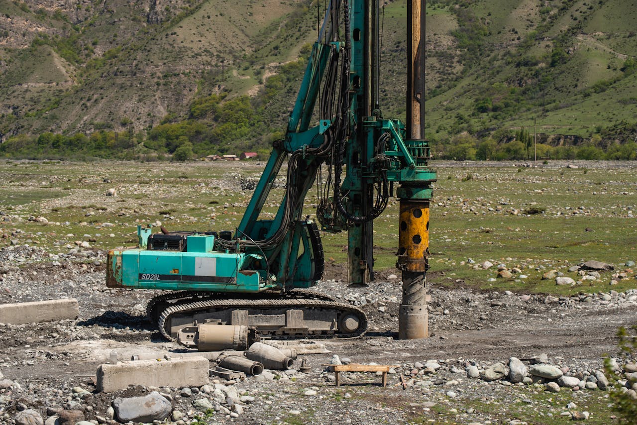 A heavy drilling machine in use on a rugged outdoor construction site.